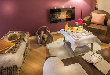 Salon zen et cocooning avec cheminée feu de bois, fauteils brun, mur prune et cozy