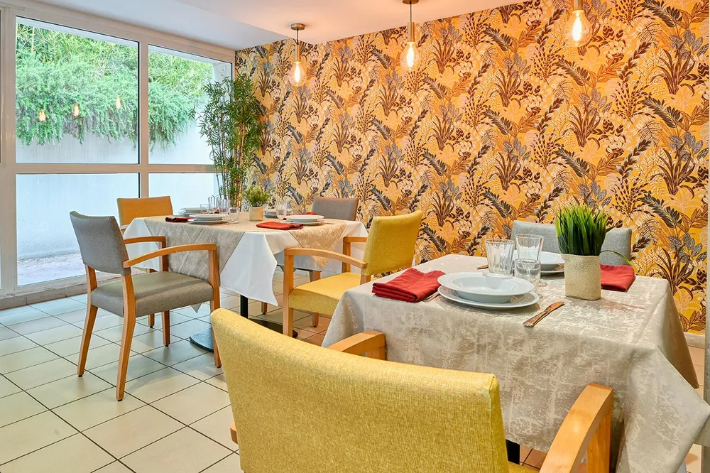 Salle de restaurant orange et jaune baie vitrée vue jardin ehpad à Marseille, Résidence Les Epis d'Or