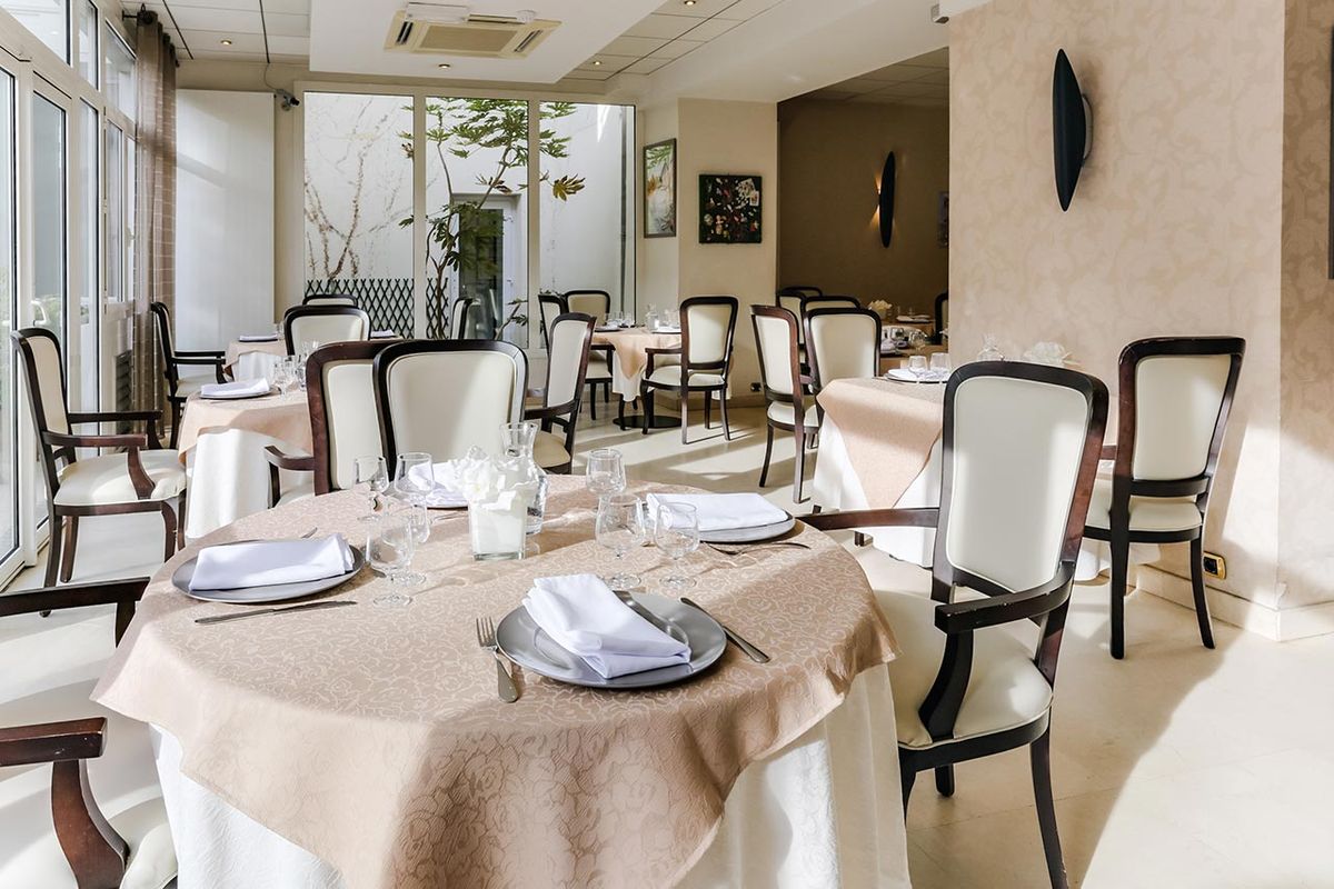Restaurant avec tables dressé, chaises blanches, résidence Le Cap à Colombes