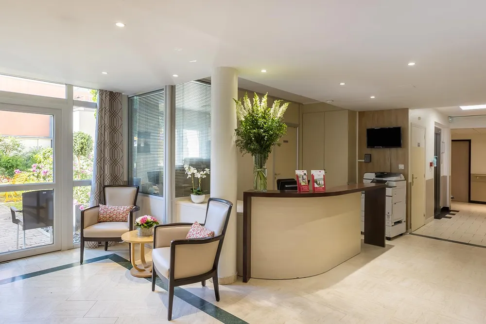 Hall moderne avec comptoir d'accueil, table, fauteuil dans un EHPAD à Colombes