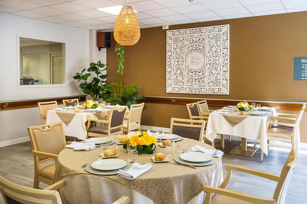 Salle commune de restaurant avec un mur marron et tabes rondes drapées et décorées
