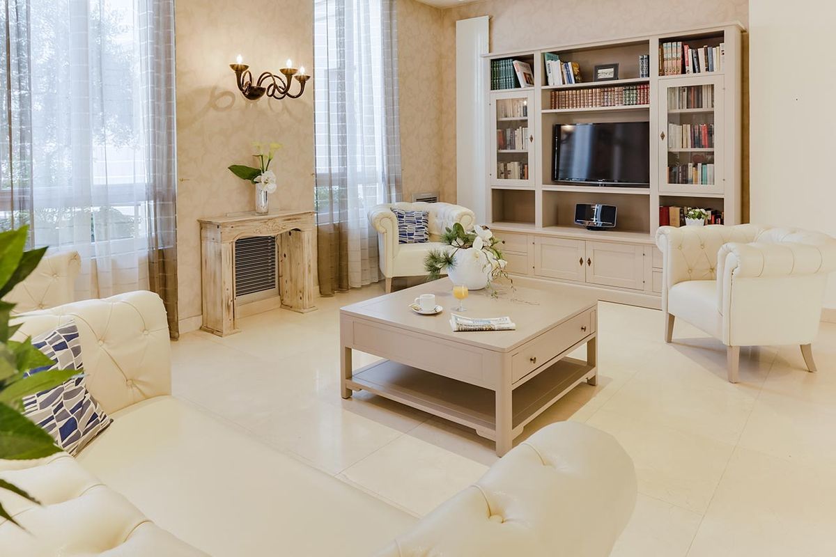 Salon cozy et lumineux avec table basse, bibliothèque, canapés blancs à l'ehpad le cap