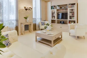 Salon cozy et lumineux avec table basse, bibliothèque, canapés blancs à l'ehpad le cap