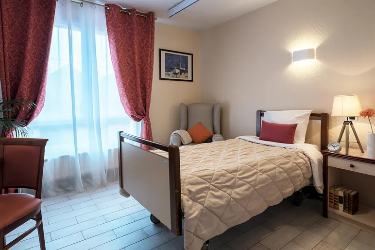 chambre individuelle avec lit simple, rideaux rouges et fauteuils, résidence Esterel à colombes