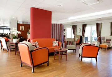 Salle commune détente sofa orange et boisé lumineux en maison de retraite à Le Rove, La Carrairade