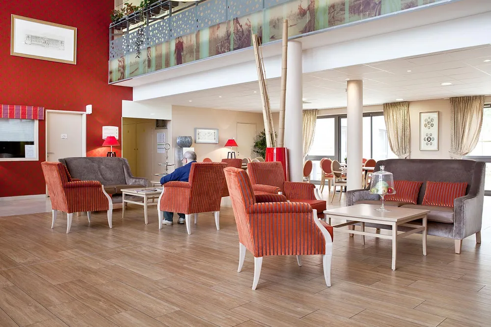 Salon lumineux fauteils duvet rouge rayures hauteur mur rouges parquet bois maison médicalisée