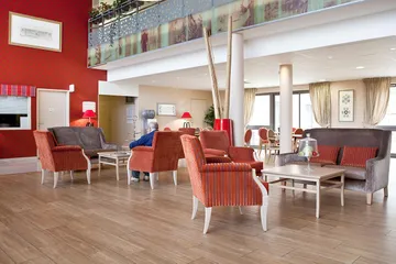 Salon lumineux fauteils duvet rouge rayures hauteur mur rouges parquet bois maison médicalisée