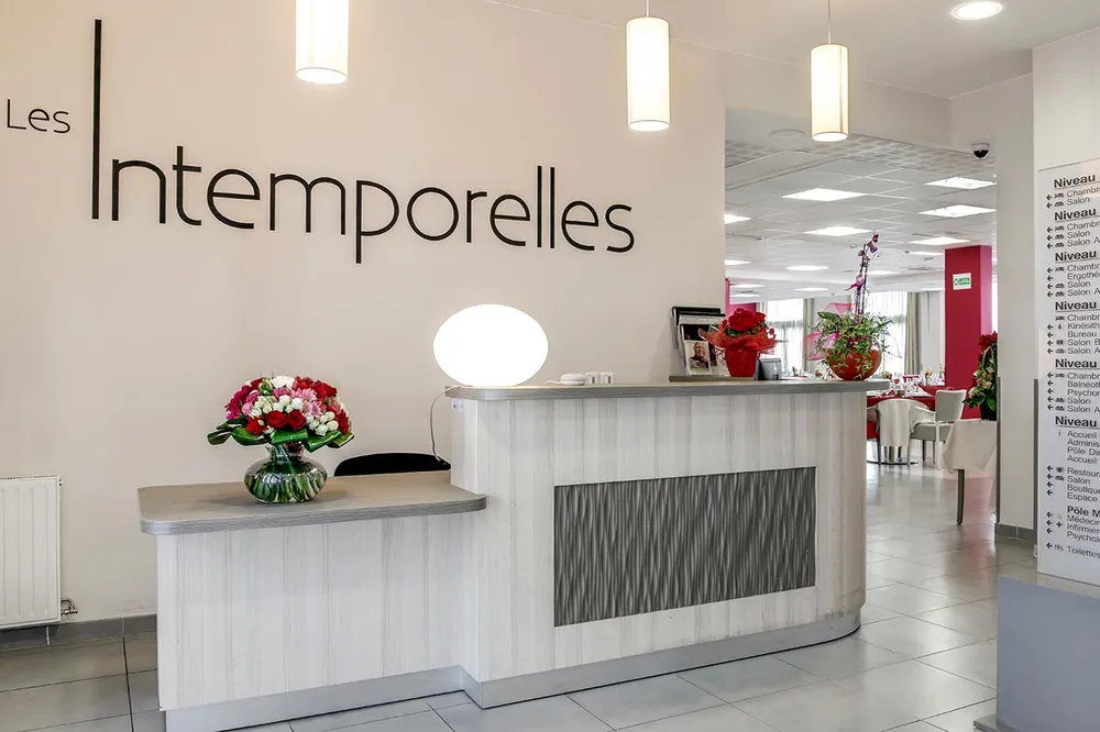 Salle de reception moderne blanc avec lumière pendante et bouquet de fleurs, mur blanc derriere avec lettres