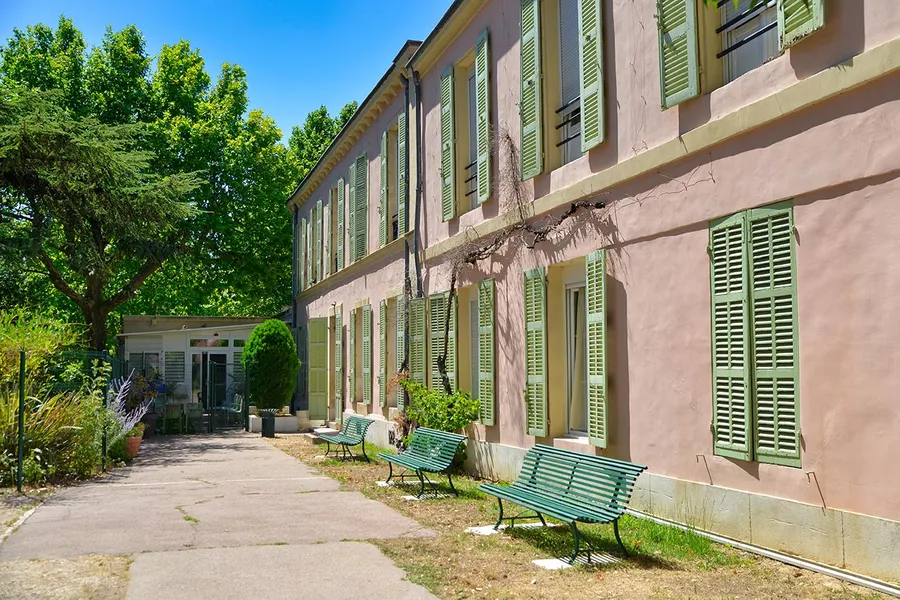 Photo immeuble rose et banc vert vue sur forêt à Marseille, ehpad Résidence Les Sèolanes