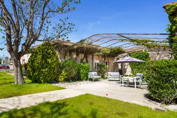 plan cour intérieur jardin avec parasol et chaises et tables, canapé jardin, verdure Les Sereins à Cheval-Blanc