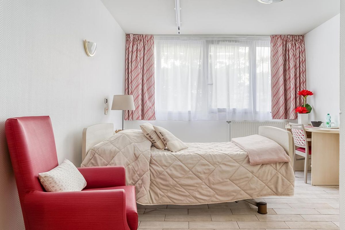 chambre avec grande fenêtre, chaise rouge et lit, ehpad à asnières