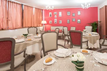 Salle à manger confortable avec tables rondes, mur rouge avec photos, résidence Esterel à Colombes