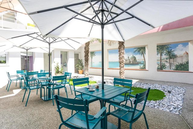 Terrasse avec tables et chaises bordeaux et parasols blanc, EHPAD La Palmeraie à Nice