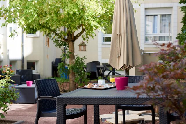 jardin cour intérieur maison de retraite Médicis à Sartrouville nature chêne et parasol beige replié