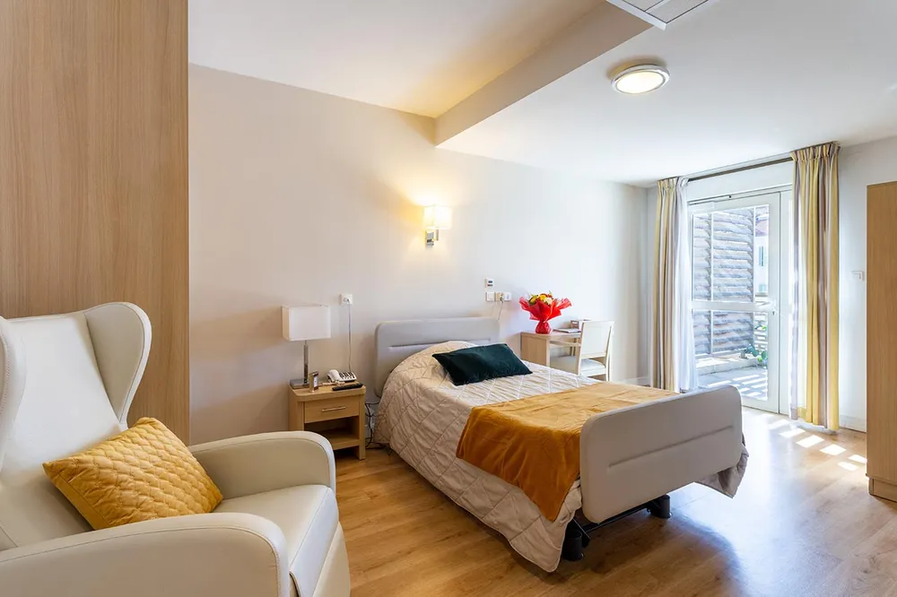 Chambre de maison de retraite lumineuse blanc et orange, avec fauteil cuir blanc à marseille résidence longchamp