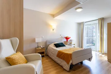 Chambre de maison de retraite lumineuse blanc et orange, avec fauteil cuir blanc à marseille résidence longchamp