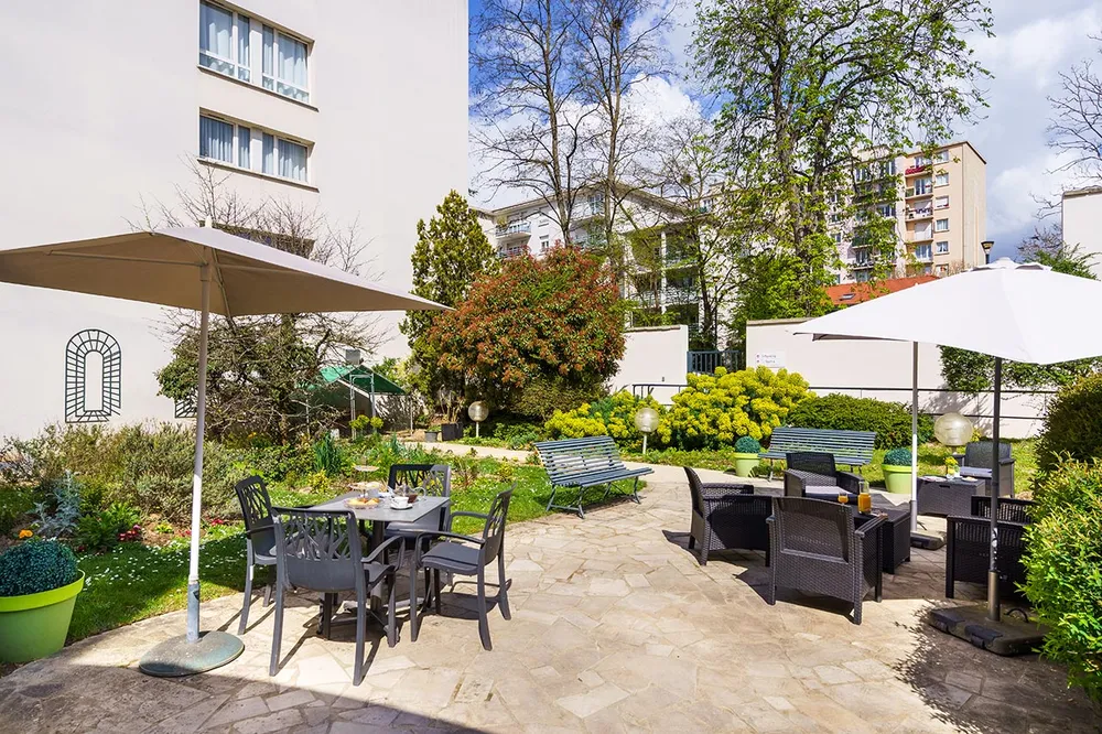 Cour intérieure Les Jardins d'Epinay parasol fauteuil jardin buisson et chaussée aménagée