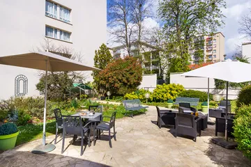 Cour intérieure Les Jardins d'Epinay parasol fauteuil jardin buisson et chaussée aménagée