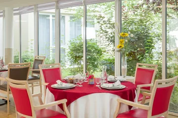 Table ronde dressée vue sur jardin bucolique baie vitrée exposition soleil lumineuse