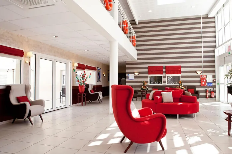 Lobby moderne soft lounge rouge et gris, lumineux en maison de retraite à Le Rove, La Carrairade