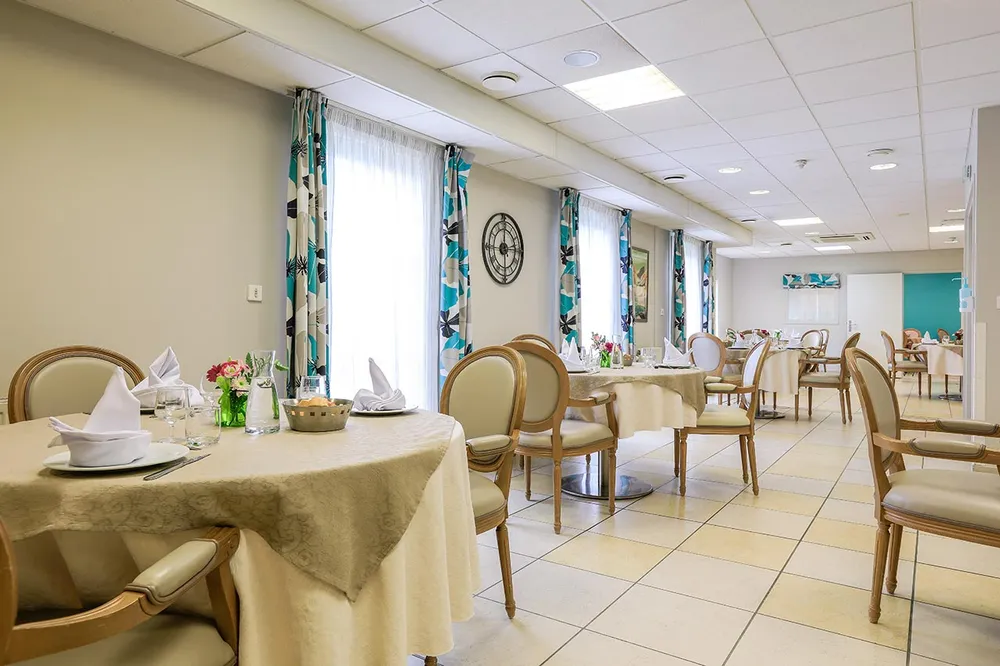 Salle de restauration maison de retraite Les Jardins Médicis à Pontpoint avec tables rondes