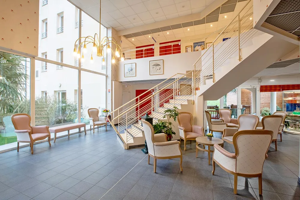 Salon lumineux luxueux premium avec lustre et baie vitrée ehpad à Trie Château, Les Jardins de la Tour
