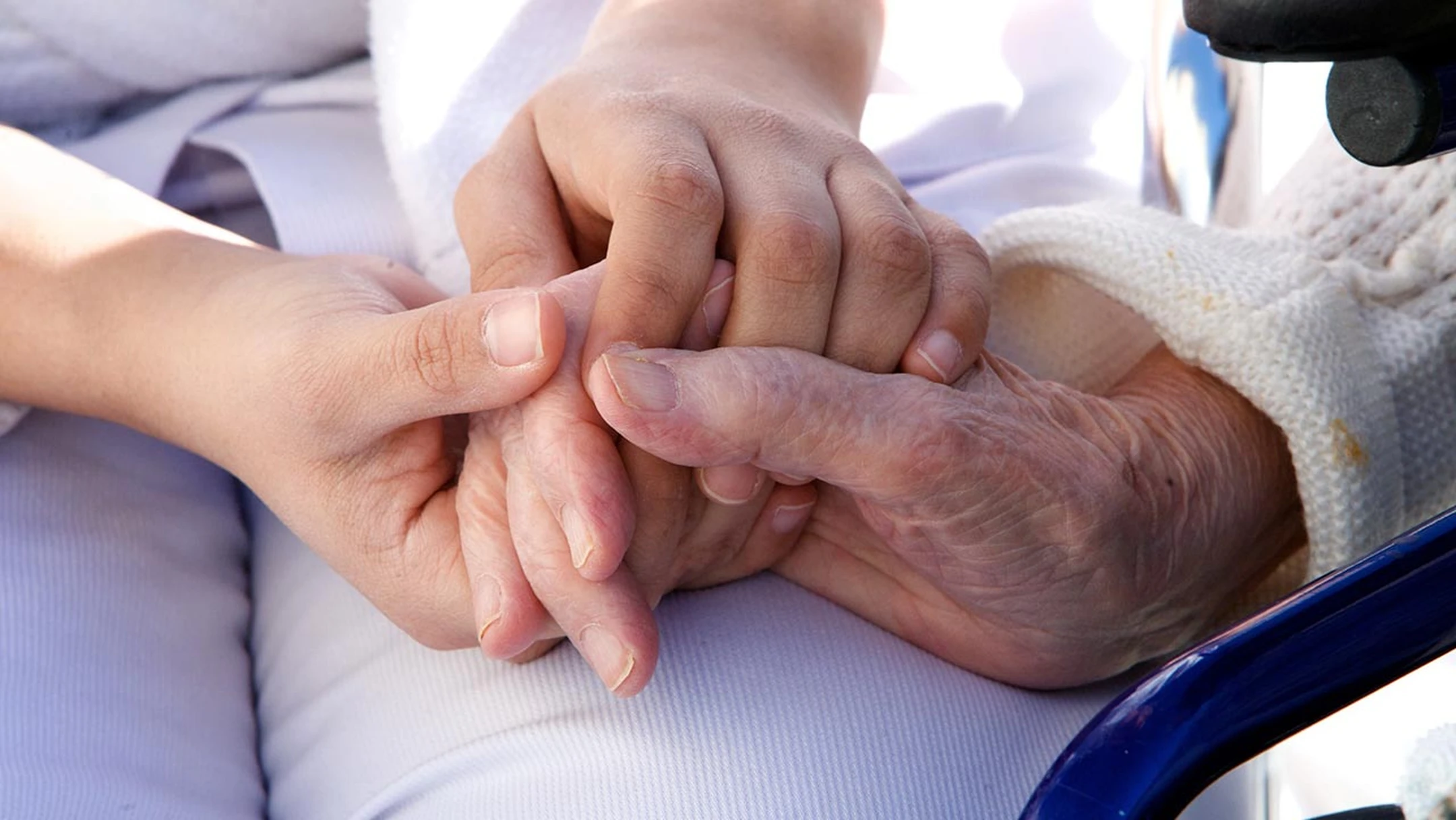 gros plan sur la main d'une personne âgée, tenue par les mains d'une personne plus jeune pour illustrer l'accompagnement de la fin de vie