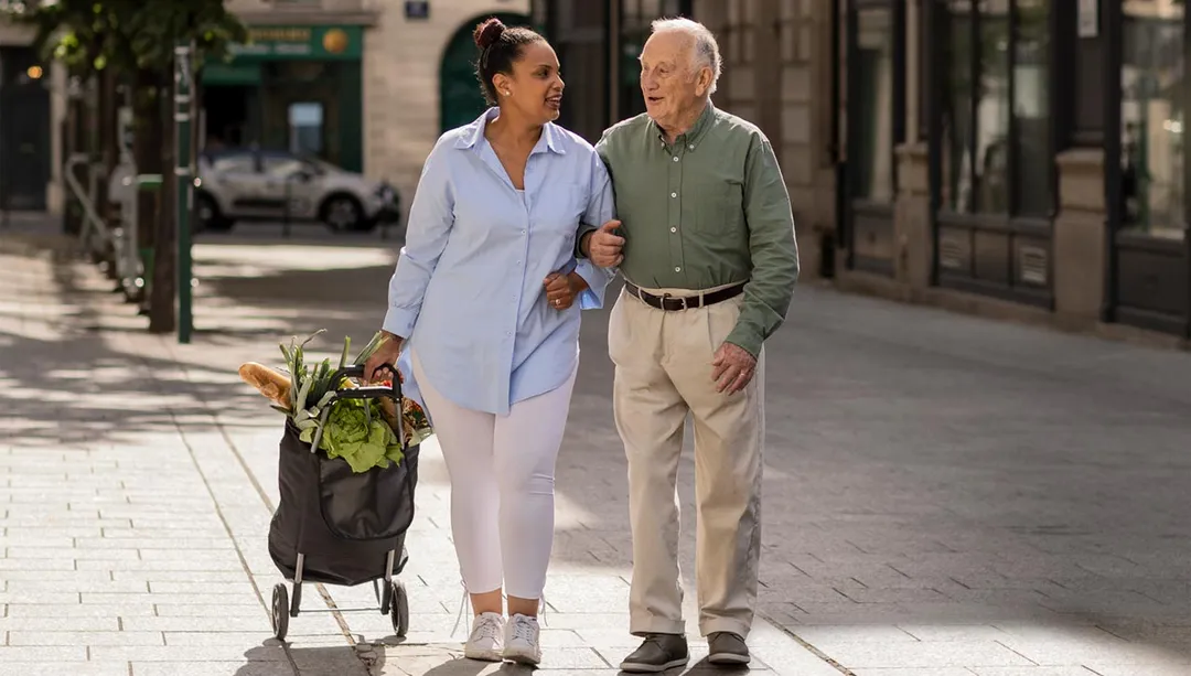 une aide à l'autonomie accompagne une personne âgée