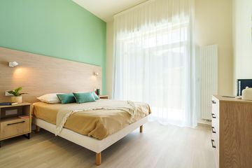 Chambre éclairée avec lit double et grande fenêtre, résidence seniors à Meschers