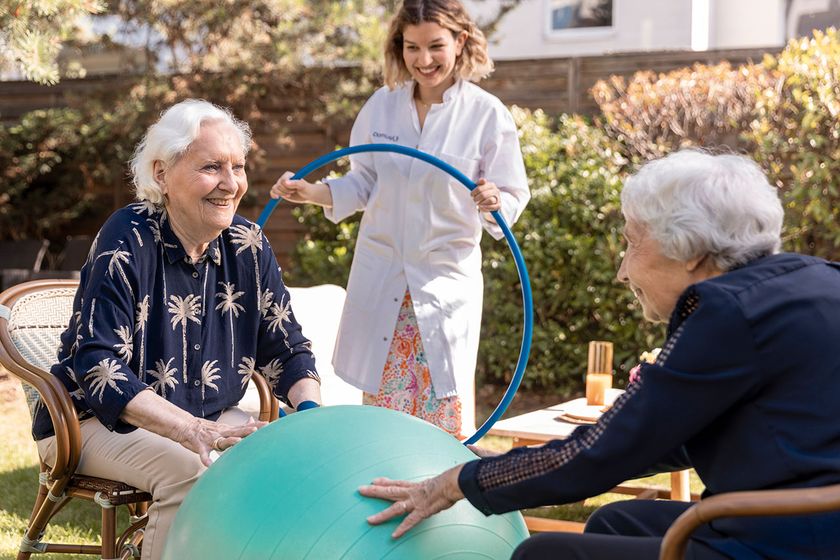 dans un ehpad, deux femmes agées font un exercice de gymnastique douce sous la supervision d'une soignante