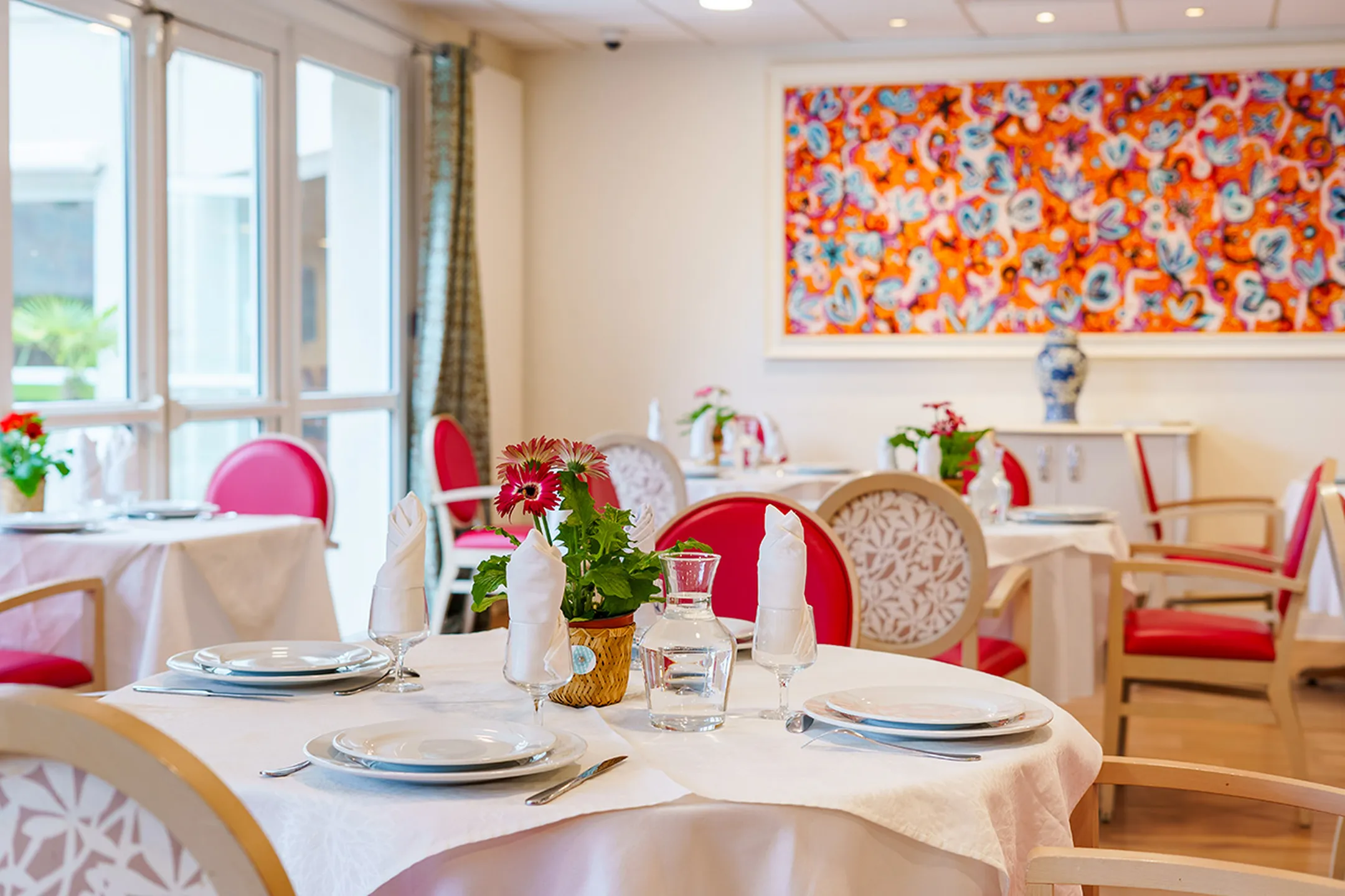 Salle de restaurant avec tables décorées, tableau coloré, maison de retraite eleusis