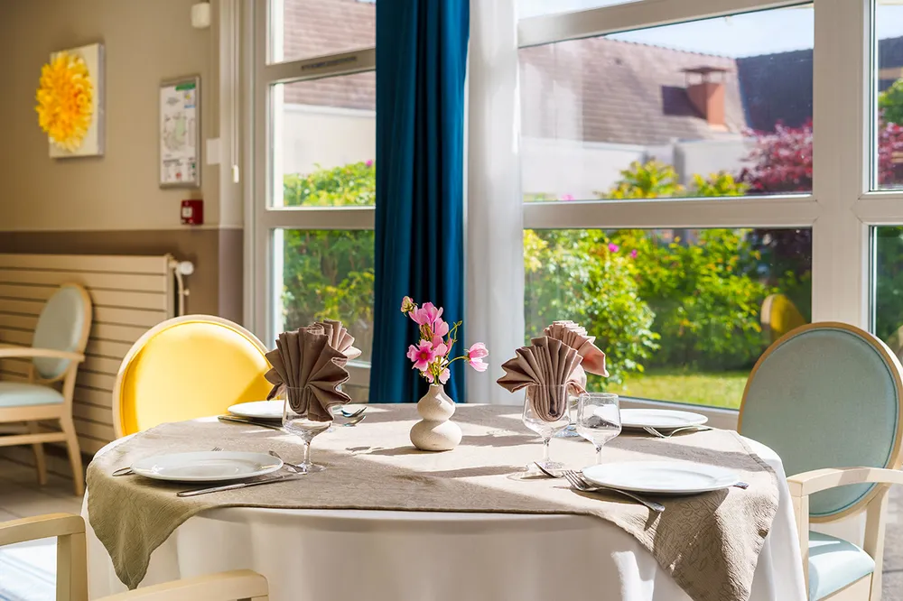 Restaurant avec table dressé et vue sur jardin résidence jardins roinville
