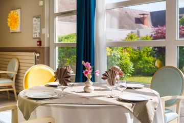 Restaurant avec table dressé et vue sur jardin résidence jardins roinville