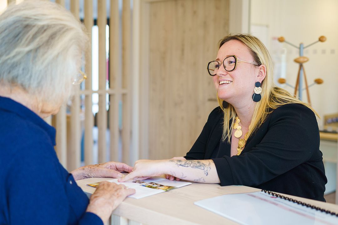 Une femme du personnel souriante qui aide une femme âgé à l'accueil, résidence à Meschers