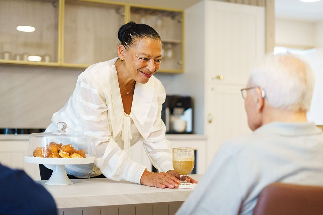 Femme souriant qui sert un homme âgé dans une résidence seniors à Suzac