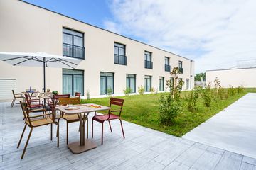 Terrasse avec parasols, chaises et tables beiges, Résidence seniors à Meschers