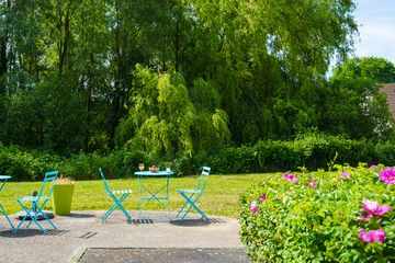 Jardin ensoleillé avec chaises et table bleues résidence jardin roinville romainville