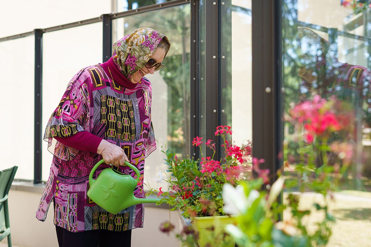 Femme âgée qui arrose les fleurs à l'ehpad tiers temps lyon