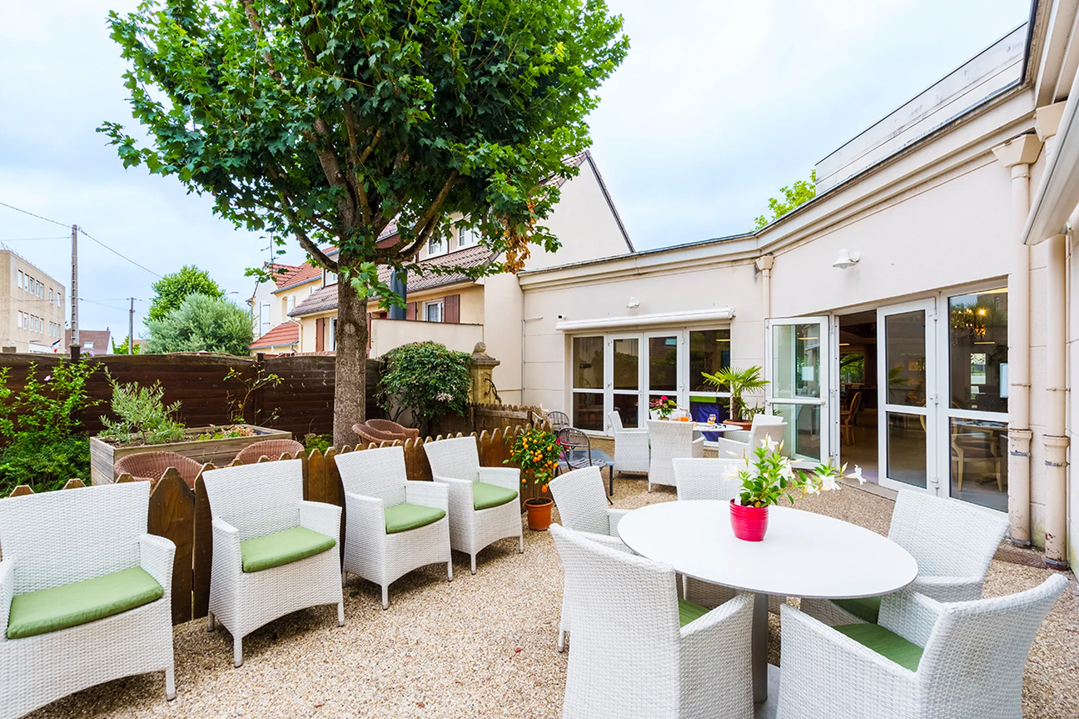 Espace exterieur avec chaises et tables blanches et coussins, résidence médicalisée à poissy