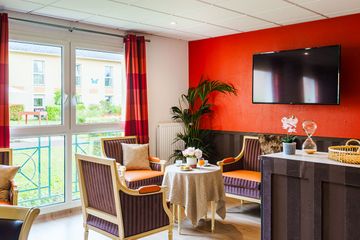 salle de repos et thé ton rouge ensoleillé avec télé La Fontaine Médicis à Gouvieux