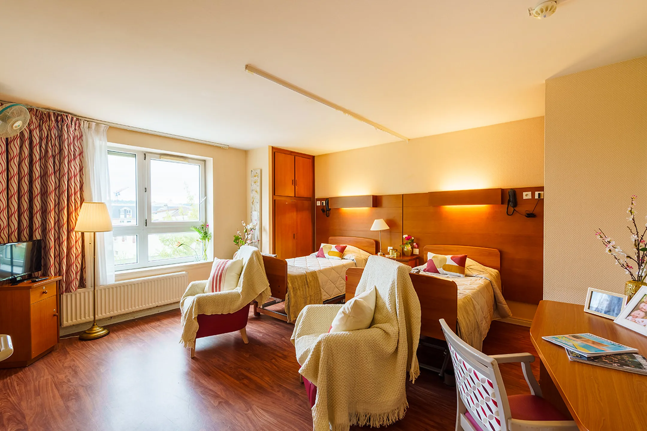 Chambre spacieuse équipée avec lit double, chaises et mobiliers, EHPAD à Poissy