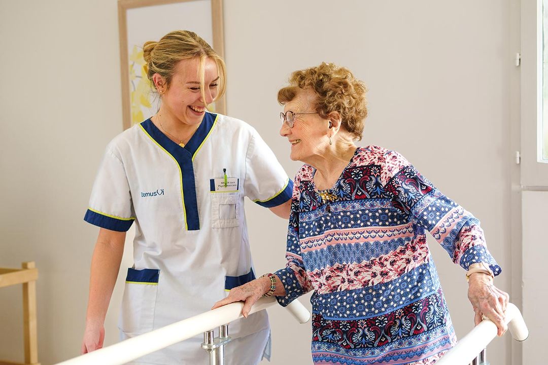Kinésithérapeute et femme âgée sourient pendant un exercice de rééducation