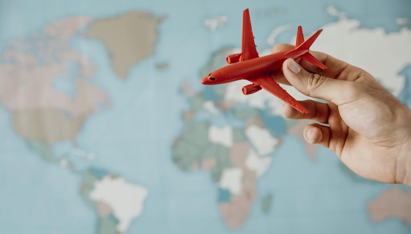 side-view-of-person-holding-airplane-figurine-over-map-scaled.jpg