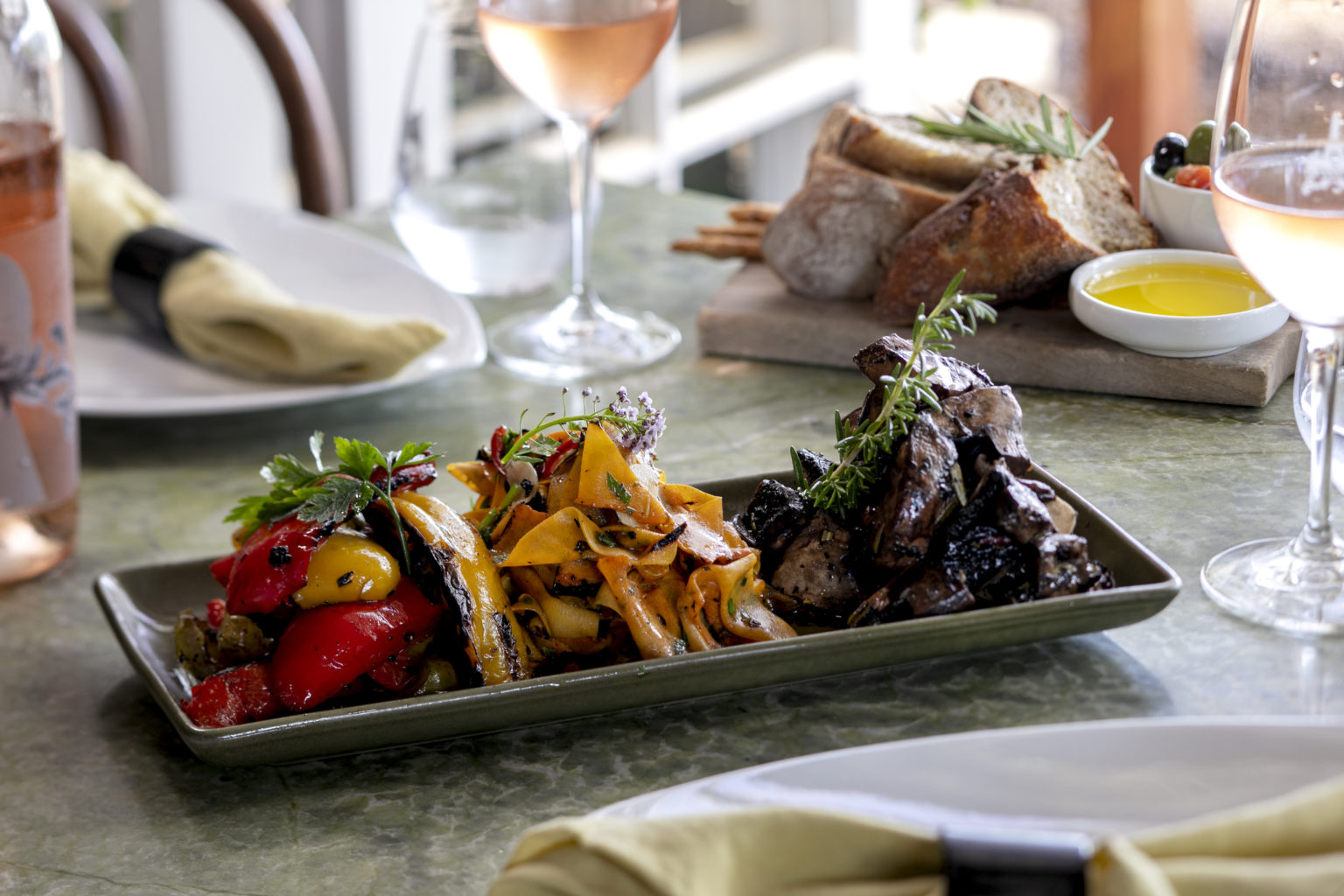 plate of roasted capsicum and mushrooms with two glasses and a bottle of rose