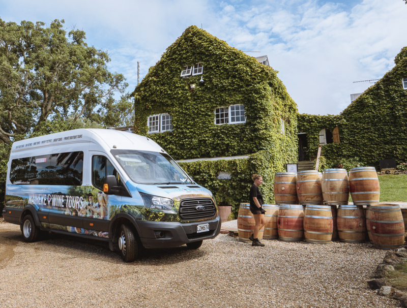 Waiheke Wine Tours Van set against the ivy-covered winery at Stonyridge Vinyard