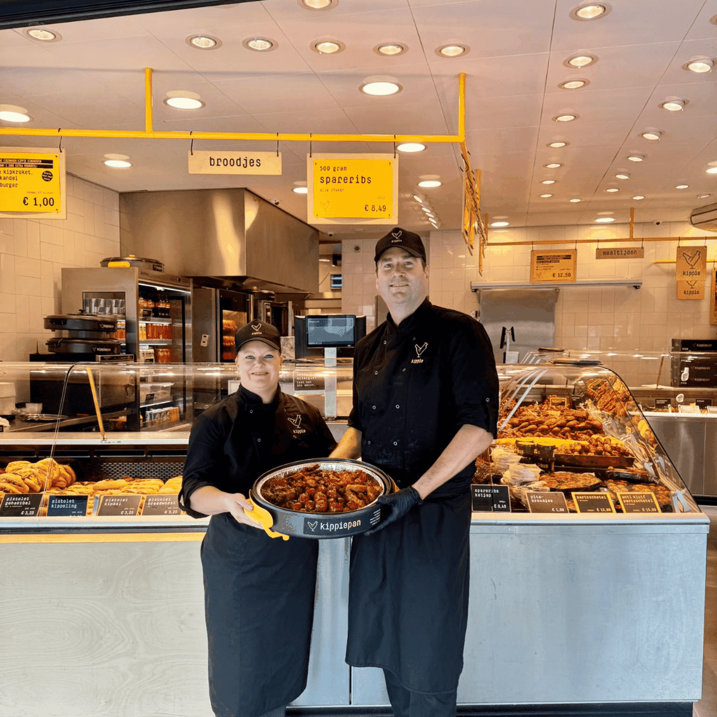 Winkel eigenaren staan vol trots voor de winkel met een Kippiepan