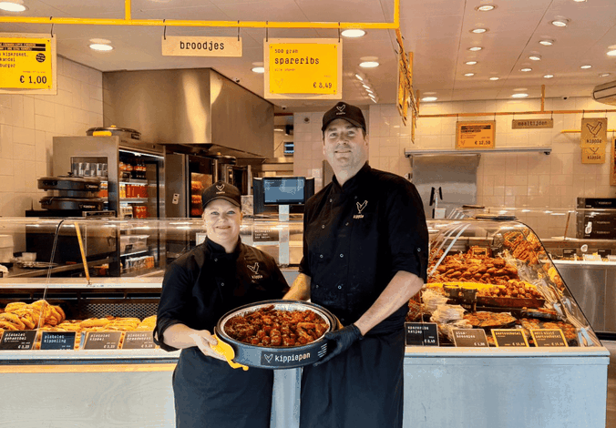 Winkel eigenaren staan vol trots voor de winkel met een Kippiepan