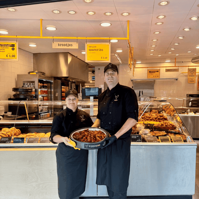 Winkel eigenaren staan vol trots voor de winkel met een Kippiepan