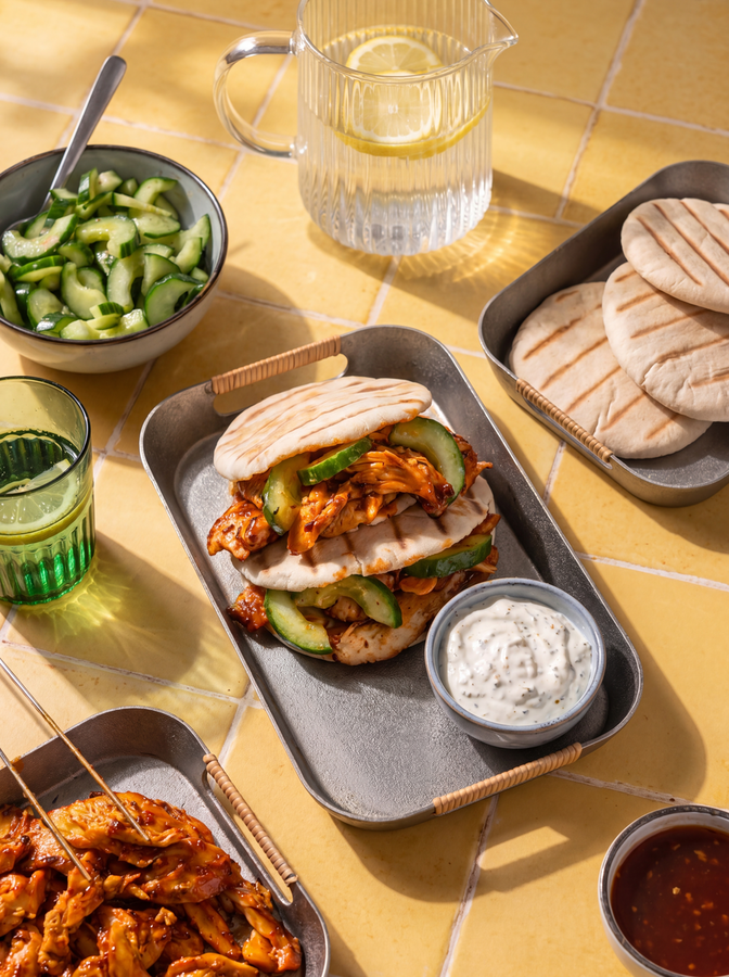 twee broodje kipdoner met komkommer en saus op een gele achtergrond