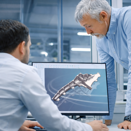 Engineers reviewing a CAD model and production data on screen, illustrating data-driven quality management and cross-department collaboration in industrial manufacturing